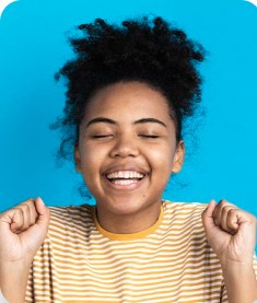 menina de pele negra, cabelo moreno e presos, sorrindo entusiasmada